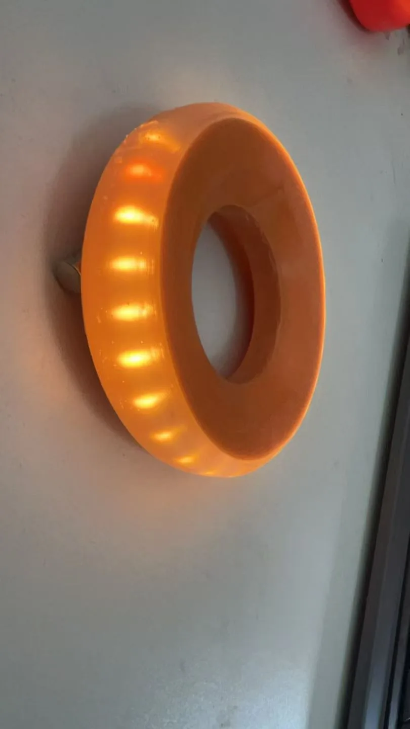 Hand holding the GLACILIT LED ringette ring, showing its size